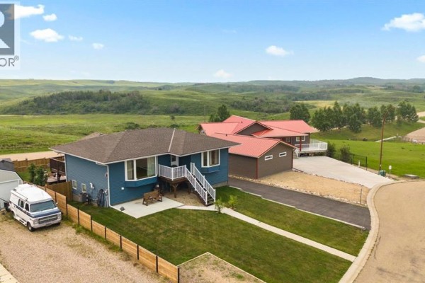 Concrete patio area next to the blue sided house with a wooden bench and railing. - 20 Marina View, Rural Stettler No  6, County Of