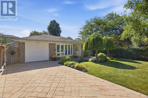 View of the house from the driveway, showing a brick pathway and green lawn. - 20 Mono Court, Brampton