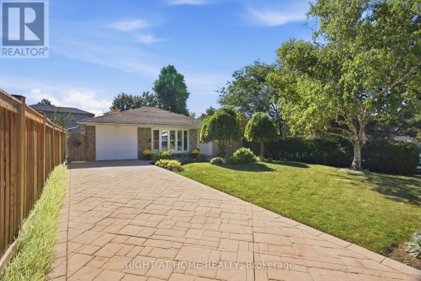Side view of the property showing a paved driveway leading to the garage and house. - 20 Mono Court, Brampton