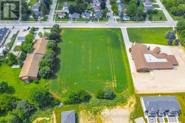 Aerial view of the Minto property showing a large green field next to a church and apartment buildings. - 20 Part Lot Con 1, Minto
