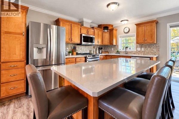 Kitchen with light wood cabinets, stainless steel appliances, and a large island with seating. - 20 Rumberger Road, Candle Lake