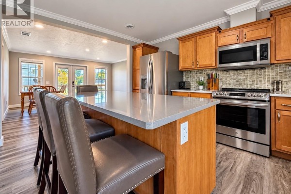 Kitchen island with light countertops and seating, facing the living and dining area. - 20 Rumberger Road, Candle Lake