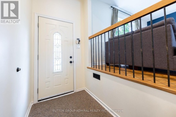 Interior entryway with a white front door, beige carpet, and a white railing leading to a living area. - 20 Sanderson Crescent, Richmond Hill