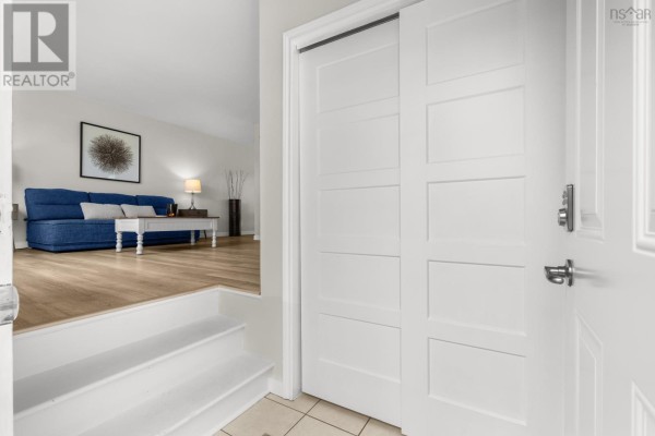 Interior view of a home entrance with white tiled floor, stairs, and a closed sliding door. - 20 Stratford Drive, Cole Harbour