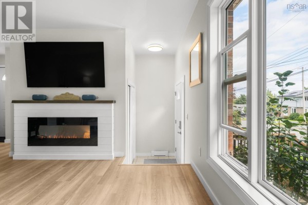 Living room with wood flooring, electric fireplace, wall-mounted TV, and a large window. - 20 Stratford Drive, Cole Harbour