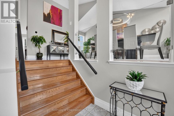 Interior view of a staircase with wood treads and railing, leading to a dining area. - 20 Sundial Court, Collingwood