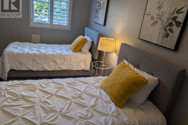 A bedroom with two twin beds, white bedding, gray headboards, and yellow pillows. - 20 Thorp Crescent, Ajax
