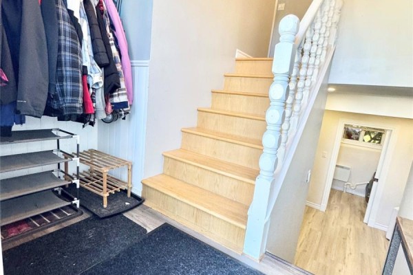Interior entryway with wooden stairs, shoe rack, coat rack, and grey walls. - 20 Tizzard Street, Lewisporte