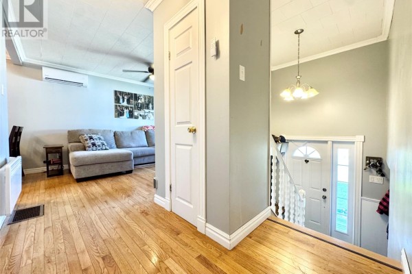 View into a living room with a grey sectional sofa and wooden floors. - 20 Tizzard Street, Lewisporte