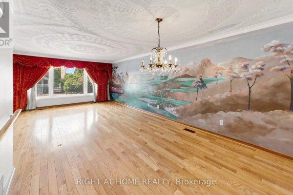 Living room with hardwood floors, large window with red curtains, and a mural on the far wall. - 20 Torrens Avenue, Toronto