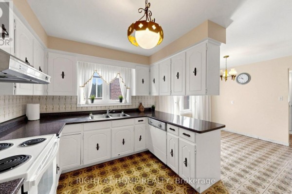 White kitchen cabinets, dark countertops, double sink, and patterned floor tiles. - 20 Torrens Avenue, Toronto