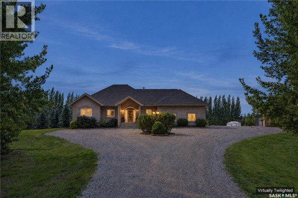 Front exterior view of the house at dusk with illuminated windows and a gravel driveway. - 20 Werschner Drive, Dundurn Rm No  314