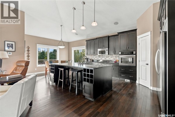 Modern kitchen with dark wood cabinets, stainless steel appliances, and a large island. - 20 Werschner Drive, Dundurn Rm No  314
