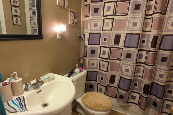 Bathroom with a white sink, toilet, and a patterned shower curtain. - 20 Wilson Street, Marystown