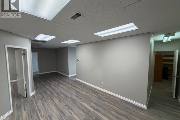 Spacious interior of commercial property with grey walls, wood-look vinyl flooring, and multiple doorways. - 200, 10009 101 Avenue, Grande Prairie