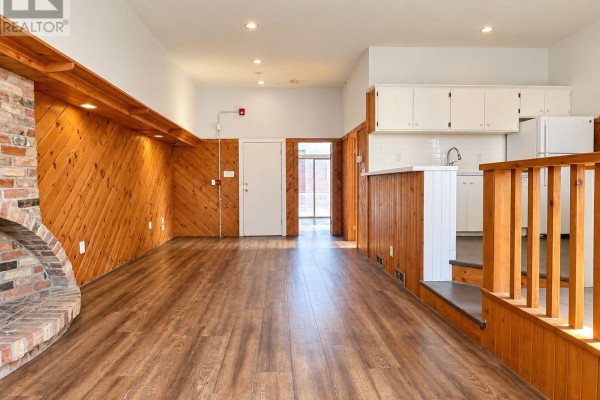 Interior room with dark wood floors, white walls, windows, and a built-in wooden bar. - 200 - 639 Yonge Street, Toronto