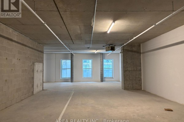 Empty commercial space with concrete floors, walls, and three windows. - 200 - 83 King Street E, Toronto