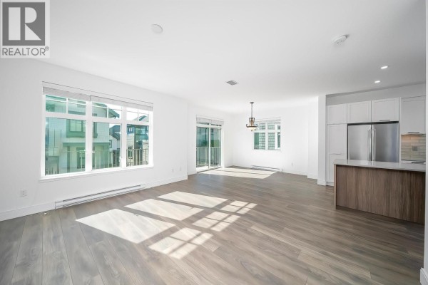 Spacious living room with large windows, hardwood floors, and modern decor. - 200 1290 Mitchell Street, Coquitlam