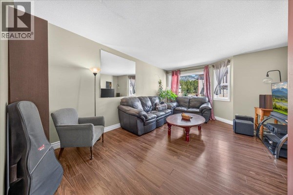 Living room with dark leather sofas, grey armchair, coffee table, and wood floors. - 200 Black Forest Trail Unit# 711, Invermere