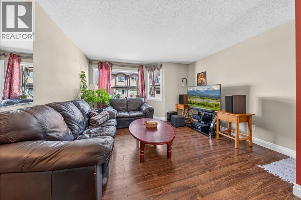 Living room showing sofas, coffee table, entertainment center with TV, and bay window. - 200 Black Forest Trail Unit# 711, Invermere