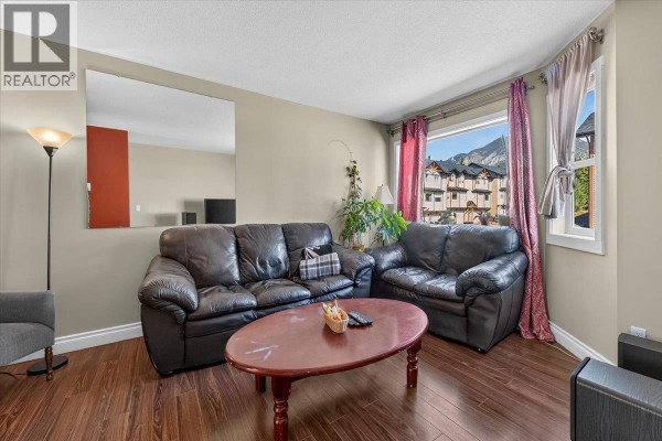 Living room with leather sofas, oval coffee table, plants, and window view. - 200 Black Forest Trail Unit# 711, Invermere