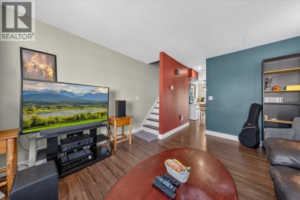 Living room with entertainment center, TV, staircase, and doorway to kitchen. - 200 Black Forest Trail Unit# 711, Invermere