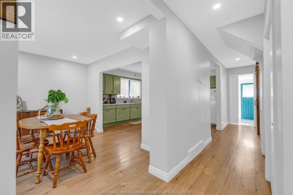 Dining area with wooden table and chairs overlooking a green kitchen with white countertops. - 200 Centre Street, Essex