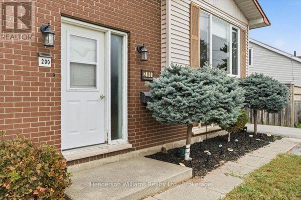 Close-up of the front entrance door with brick facade and decorative shrubs. - 200 College Street E, Belleville