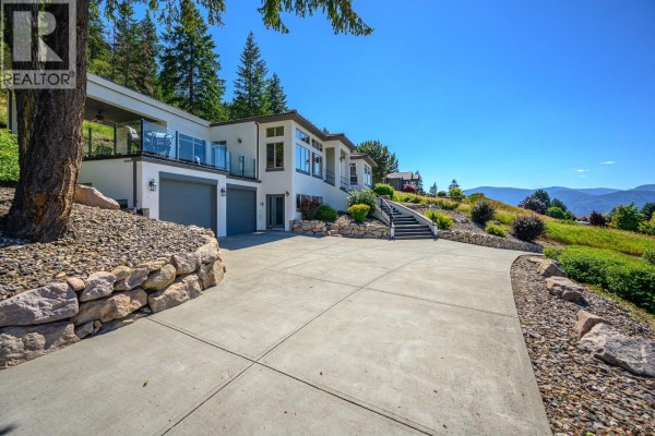 Close-up of the entrance with stone steps and a wooden front door under a covered porch. - 200 Melrose Court, Vernon
