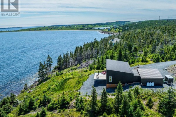 Wide aerial view of a modern black house and garage on a treed hillside overlooking a bay. - 200 Middle Road, Kingsburg