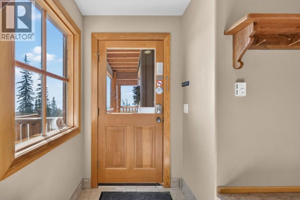 Interior view of a wood-paneled entryway with a glass-paneled door and a window. - 200 Moonshine Crescent Unit# 11, Big White