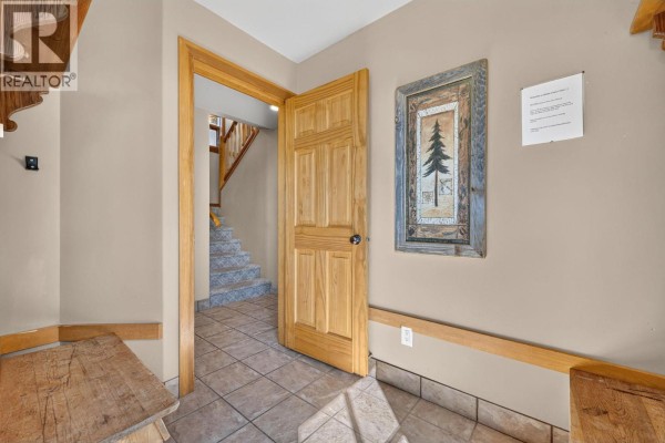 View from the entryway to a staircase with stone steps and a wooden door ajar. - 200 Moonshine Crescent Unit# 11, Big White
