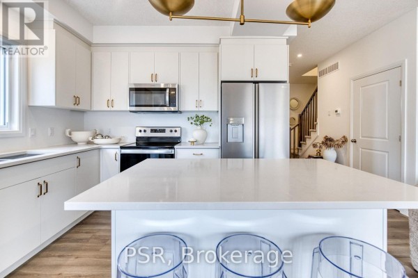 Modern kitchen with white cabinets, island, and stainless steel appliances - 200 Rivergreen Crescent Waterloo