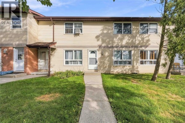 Exterior view of a light yellow townhouse complex with green grass. - 200 St Clair Boulevard Unit# 44, St Clair