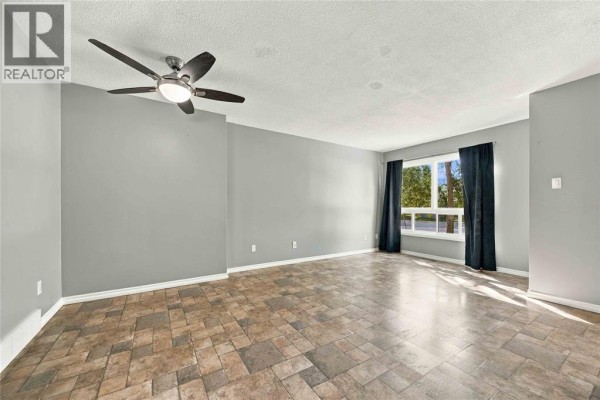 Living room with gray walls, beige tile floors, ceiling fan, and large window. - 200 St Clair Boulevard Unit# 44, St Clair