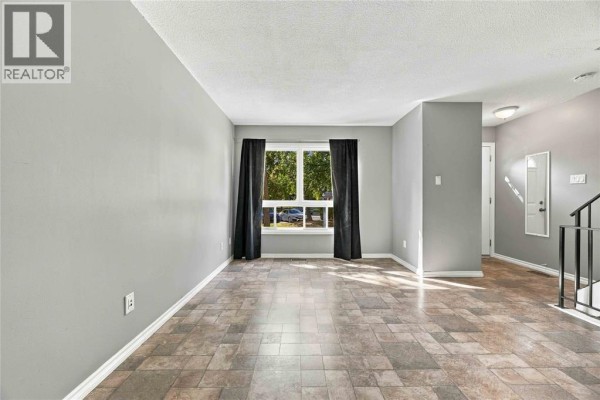 Living room with light grey walls, large window, and checkered tile flooring. - 200 St.clair Boulevard Unit# 44, St Clair