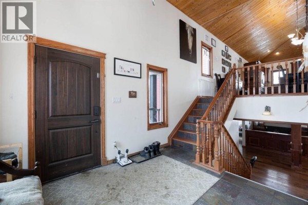 Interior foyer with a dark wood front door, slate tile floor, and wooden staircase. - 200 Weiss Drive, Saprae Creek