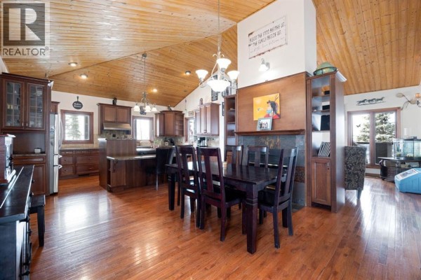 Dining area with a dark wood table and chairs, adjacent to a kitchen with dark wood cabinets. - 200 Weiss Drive, Saprae Creek