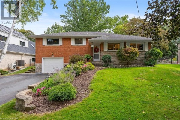 Front view of a brick house with stone accents, garage, and landscaped garden. - 200 Woodview Crescent, Ancaster