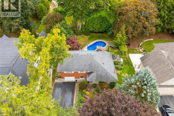 View of a spacious front lawn with mature trees and a brick house. - 200 Woodview Crescent, Ancaster