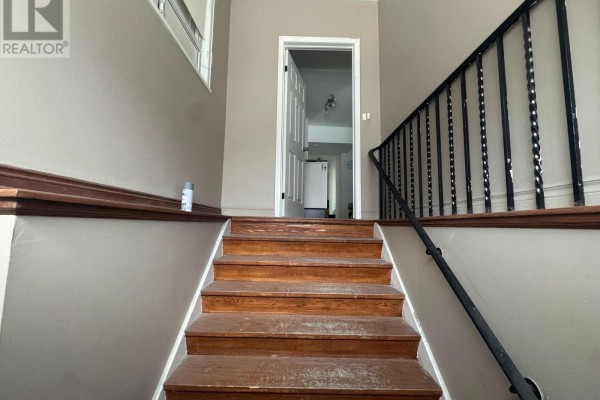 Interior staircase with wooden steps and black railing leading to upper level. - 2000 Eglinton Avenue W, Toronto