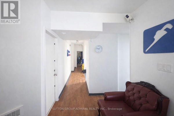 Hallway with wooden flooring, wall clock, and seating area. - 2000 Eglinton Avenue W, Toronto
