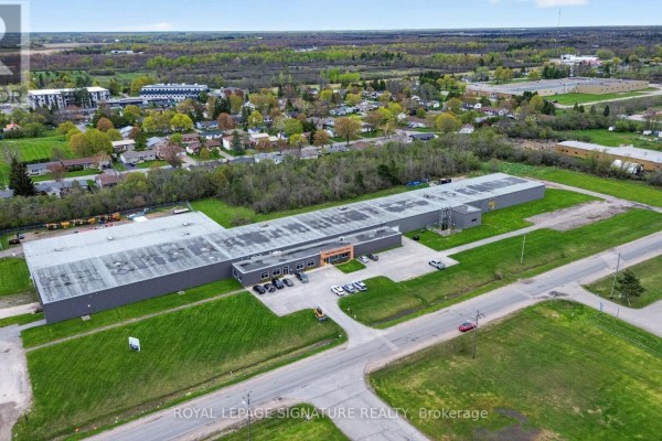 Aerial view of a long commercial building with a grey facade and surrounding green landscape. - 2000 Rogers Road, Perth
