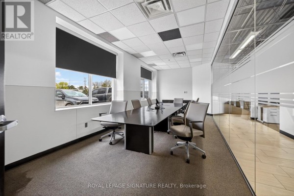 Boardroom with a large dark table, chairs, and glass-walled offices visible. - 2000 Rogers Road, Perth