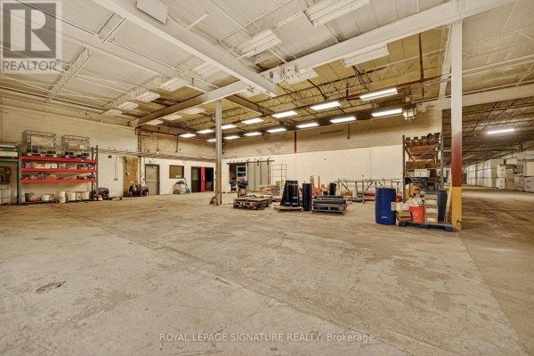 Warehouse interior with concrete floor, high ceilings, metal shelving, and storage boxes. - 2000 Rogers Road, Perth