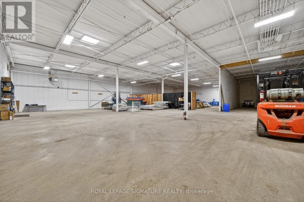 Spacious warehouse interior with concrete flooring, white ceiling, lighting, and an orange forklift. - 2000 Rogers Road, Perth