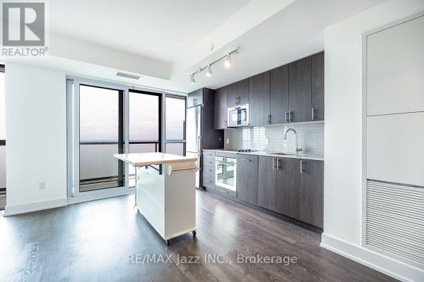 A contemporary kitchen with dark wood cabinets, stainless steel appliances, and a large window. - 2001 - 2550 Simcoe Street N, Oshawa