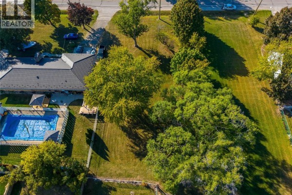 Aerial view of a house with a pool and green lawn, next to trees. - 2002 St. Clair Parkway, Sarnia