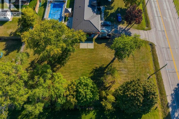 Aerial view of a grassy yard with trees, a house, and a street. - 2002 St. Clair Parkway, Sarnia