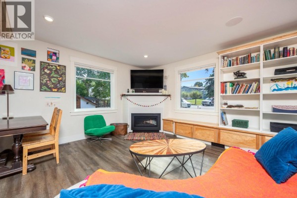 Living room with fireplace, built-in white bookshelves, and large windows overlooking the street. - 2003 30 Avenue, Vernon